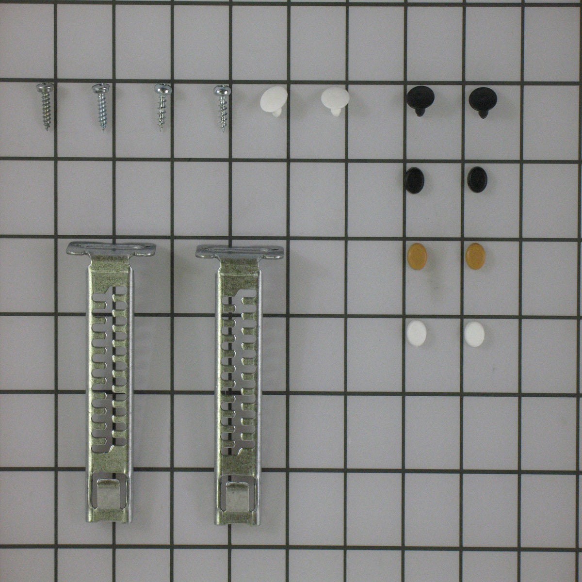 Set of small metal brackets and screws on a grid background